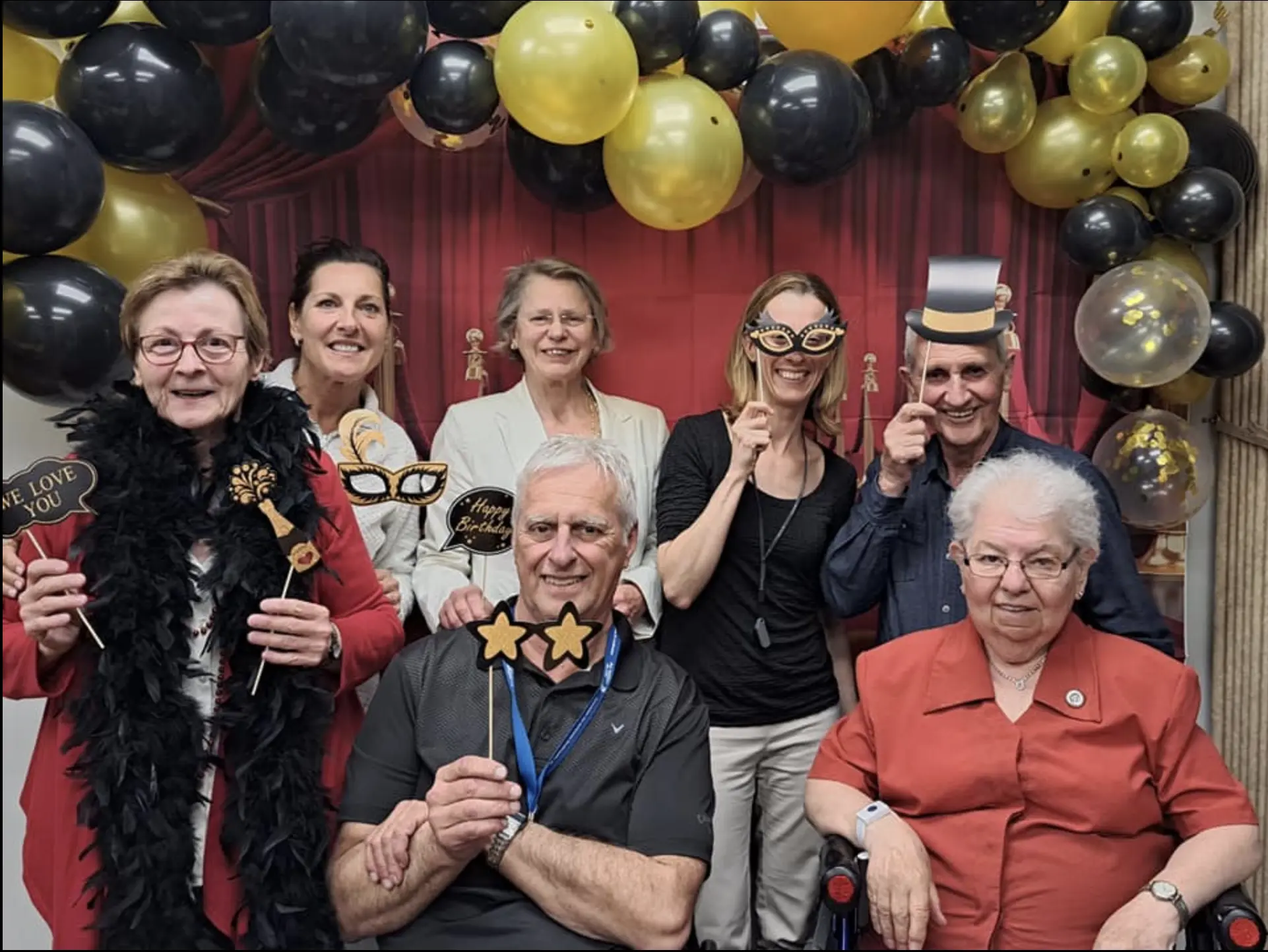 Personnes posant avec accessoires festifs et ballons.