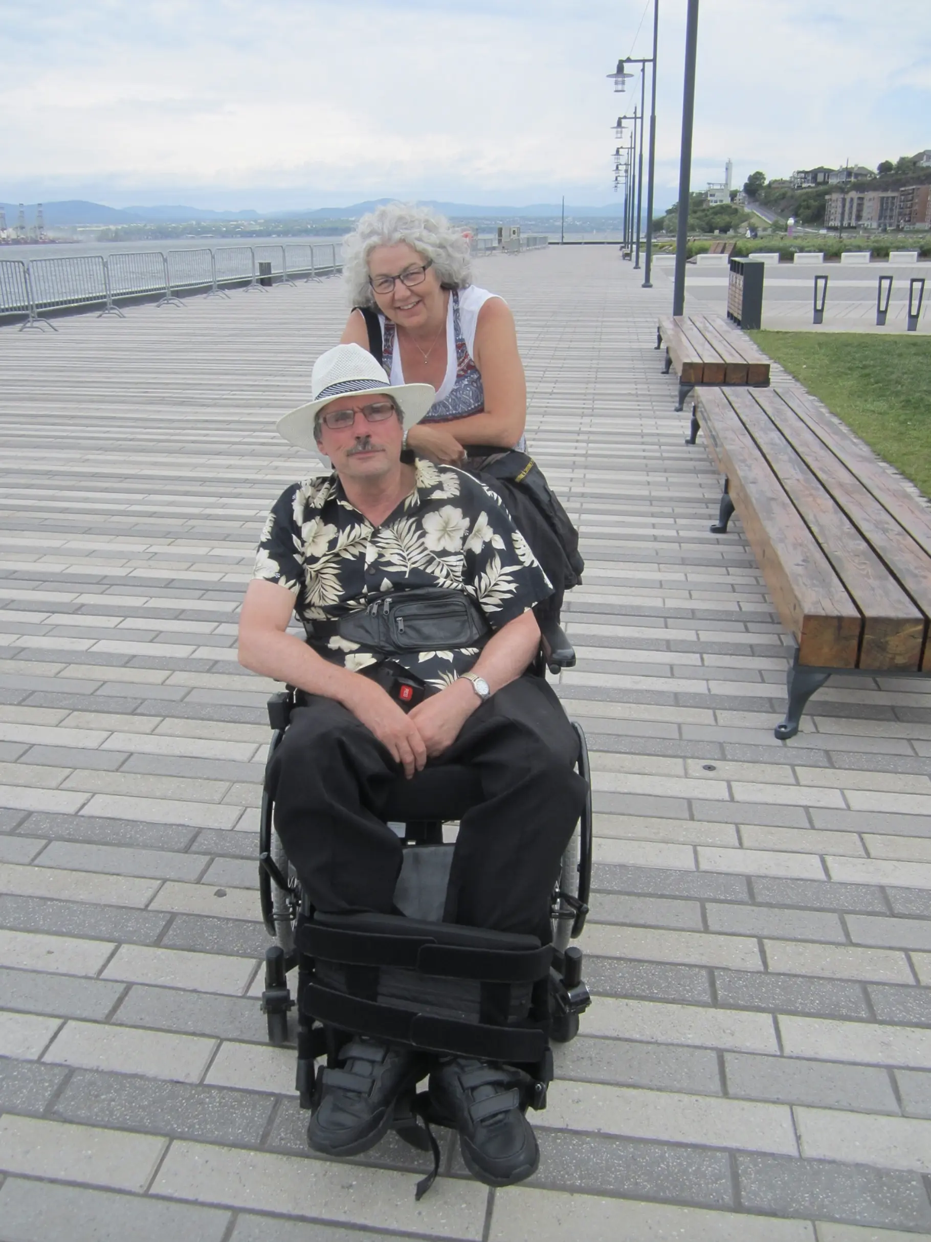 Couple souriant sur une promenade en bord de mer.