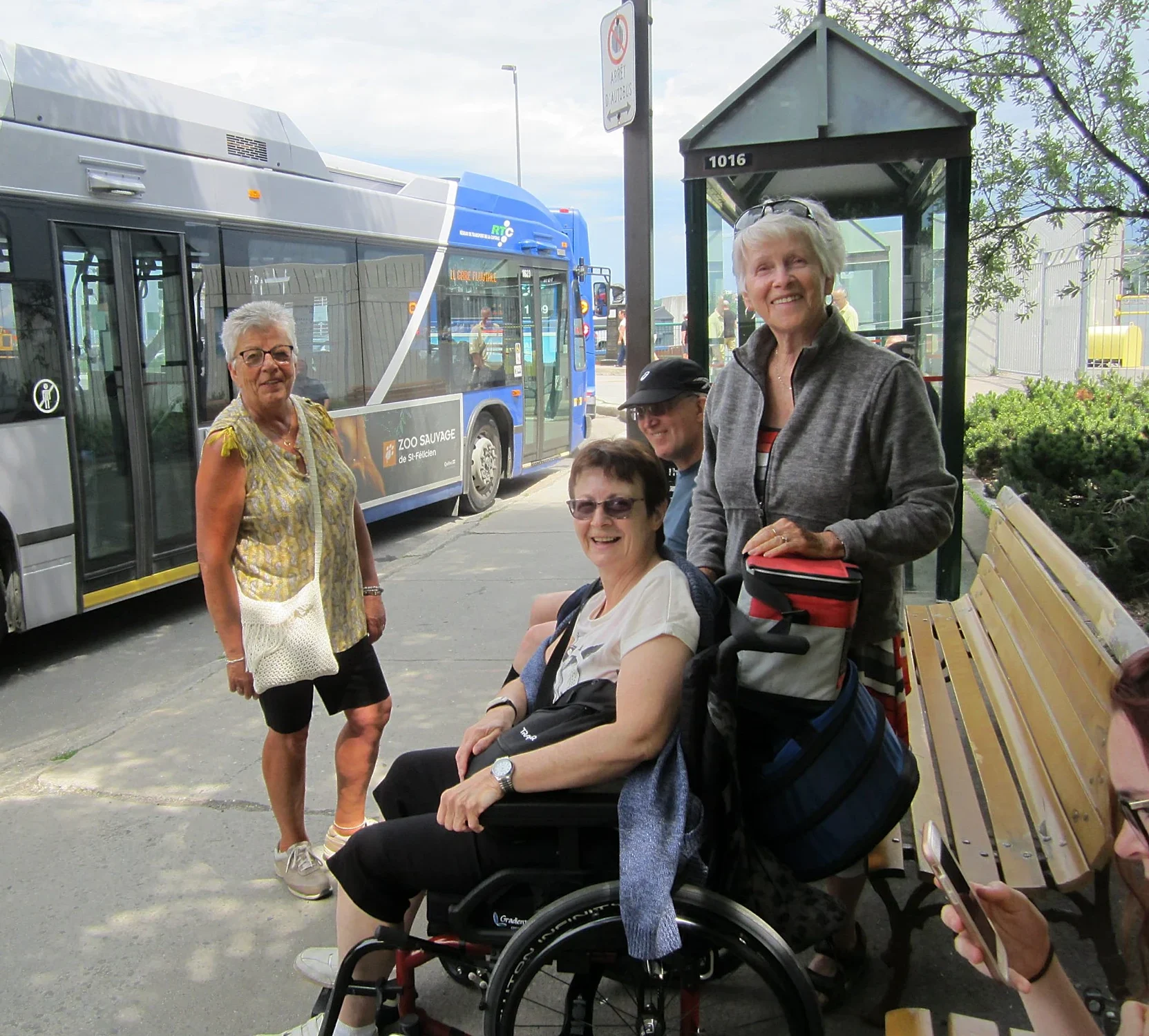 Groupe de personne avec l'une d'entre elle en chaise roulante a un arrêt d'autobus